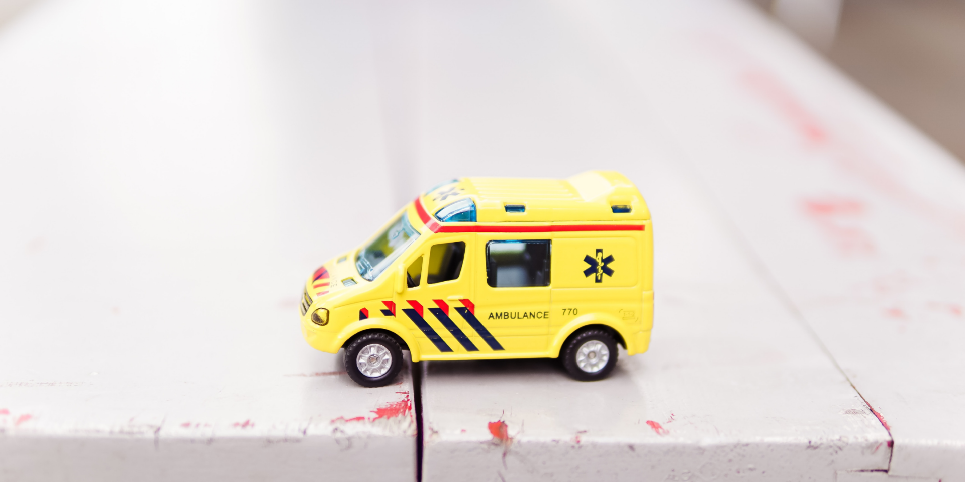 A toy ambulance on a white bench