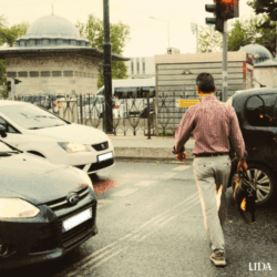 Man crossing road in between cars in traffic