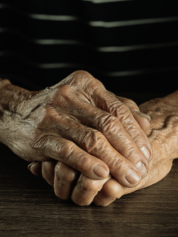 Elderly persons hands on table close up